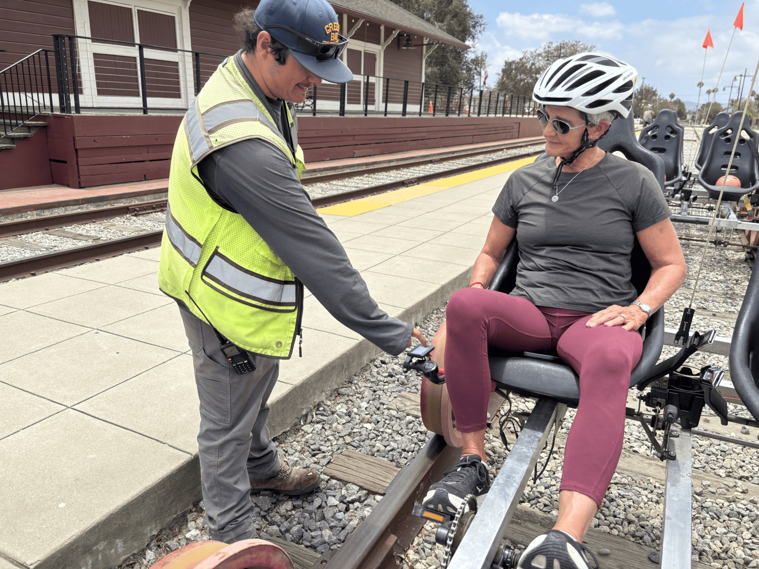 Person in wheelchair receiving assistance at train station platform.