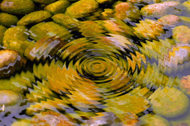 Colorful rocks with water creating a rippling effect and spiral pattern.